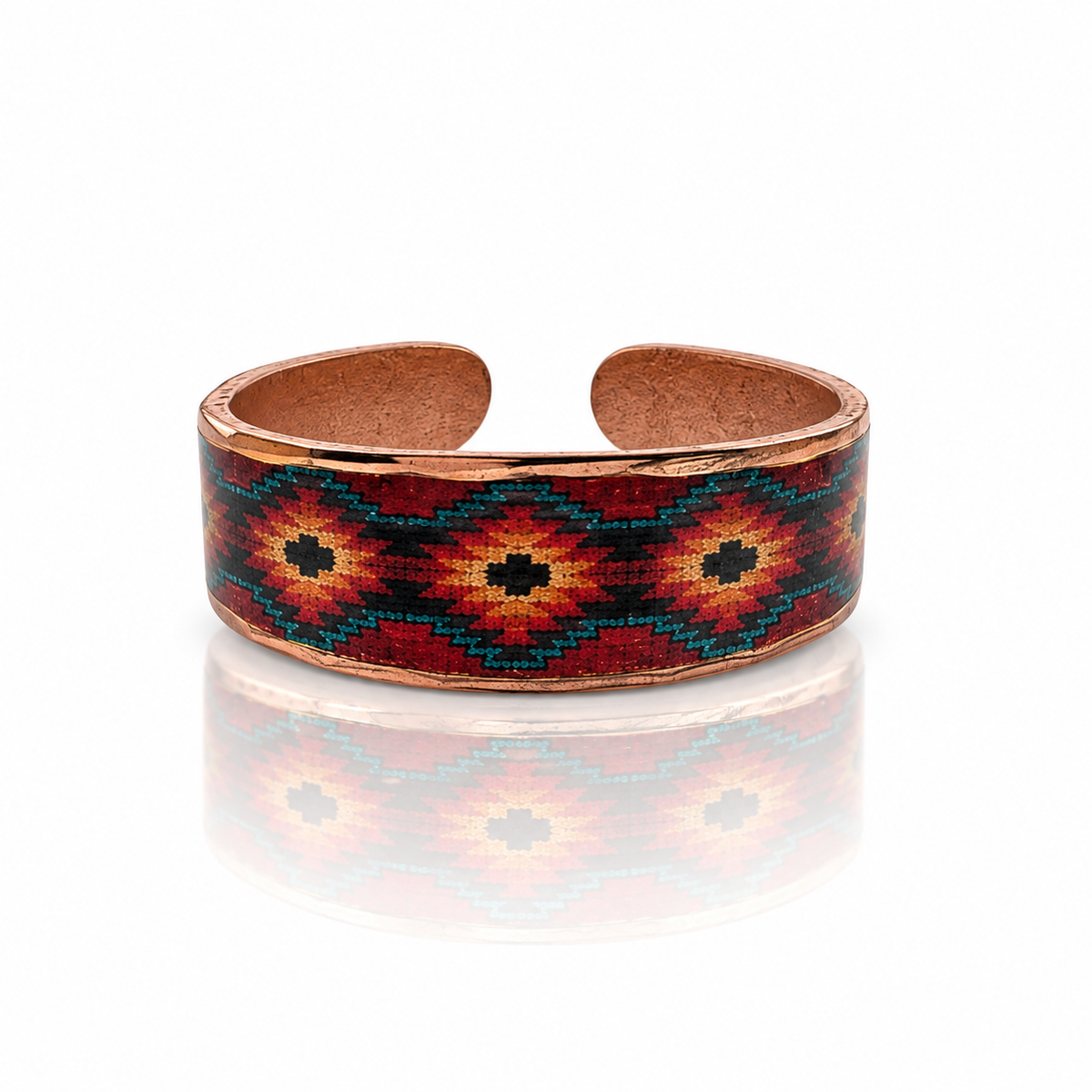 A copper-toned open cuff bracelet featuring a Southwestern-style geometric pattern with red, orange, black, and teal beads, displayed on a clean white background with a soft reflection below.